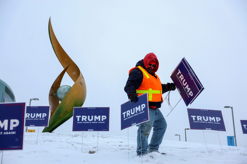 A person places signs before a rally by Republican presidential candidate and former US President Donald Trump in Manchester, New Hampshire, on January 20, 2024.
