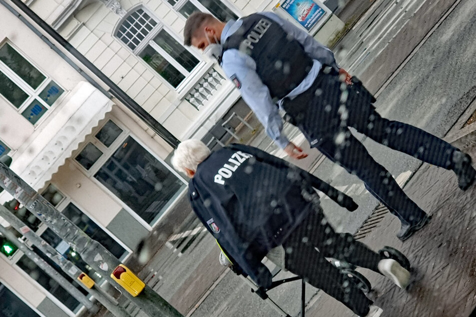 Der Polizist gab der Dame seine Jacke, da es zu regnen anfing.