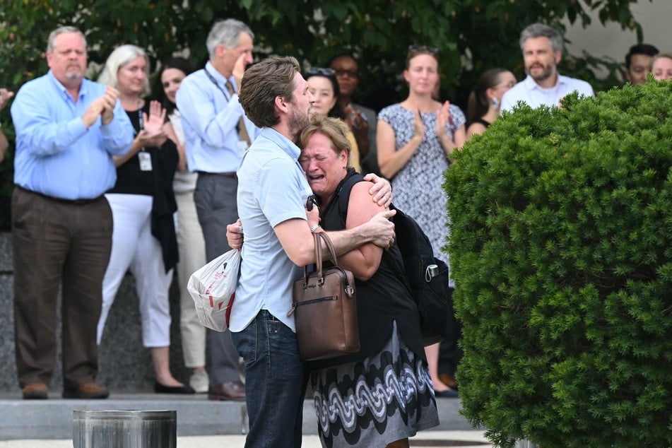 Supporters applaud as fired US State Department workers embrace while leaving the building in Washington, DC, on Friday.