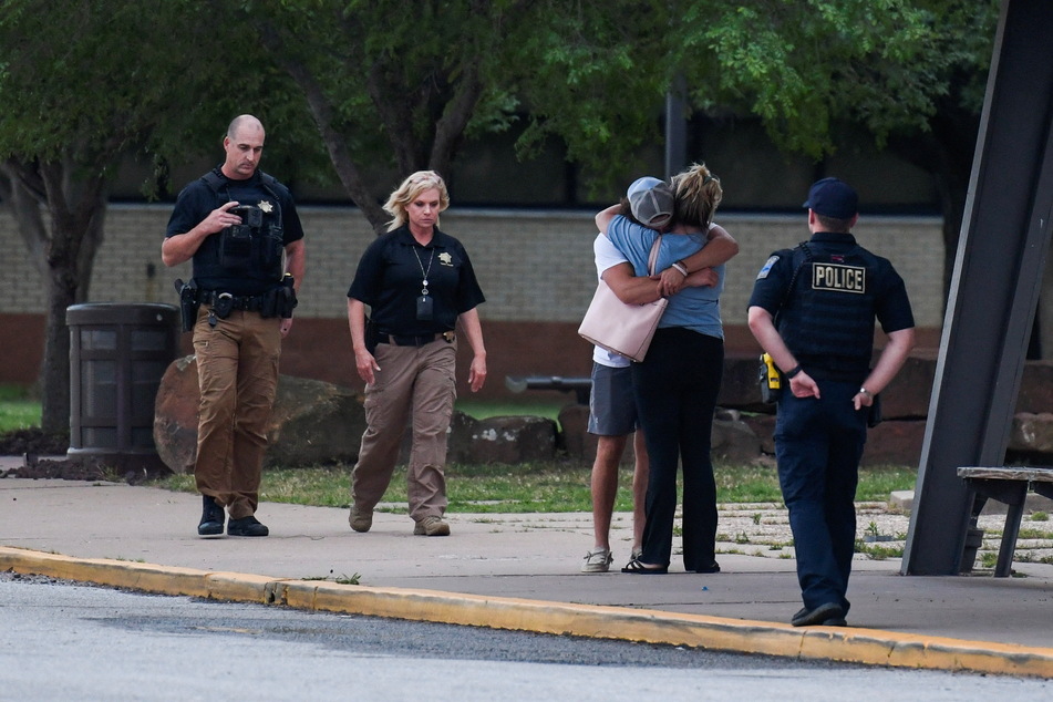 Distraught people hug as police watch on in the aftermath of the shooting.