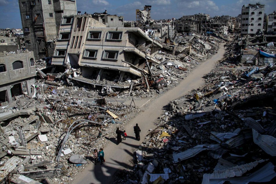 Menschen gehen an den Ruinen von Gebäuden vorbei, die durch israelischen Luftangriff im Flüchtlingslager Dschabalia zerstört wurden.