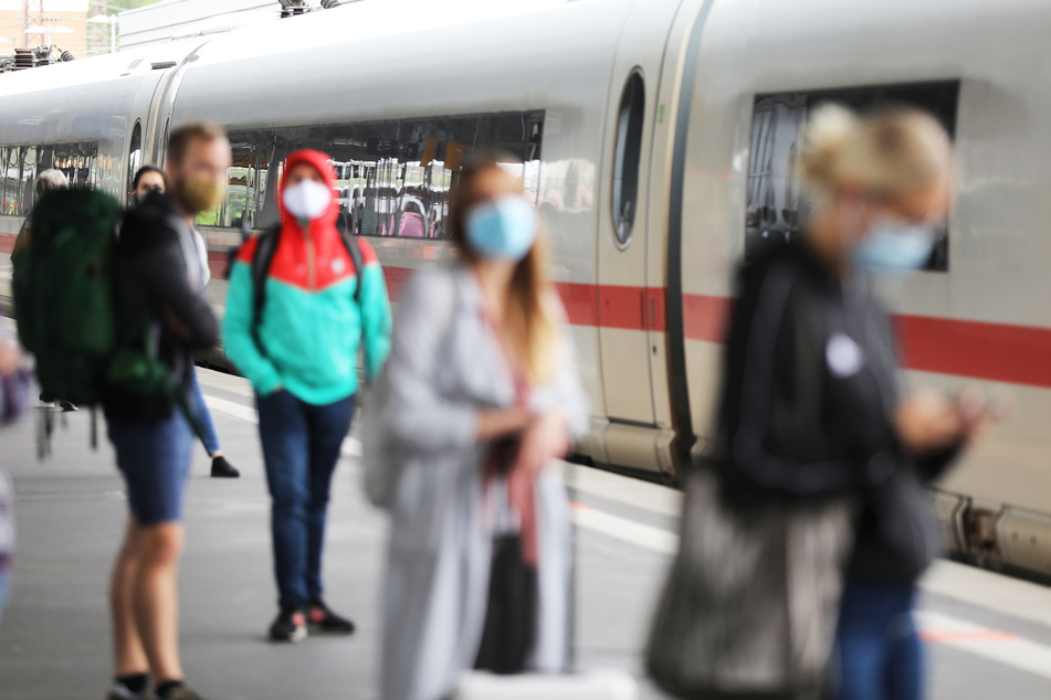 Reisende stehen auf dem Hauptbahnhof mit Masken an einem Zug. Die Bundespolizei kontrolliert zurzeit, dass auch alle Zuggäste ihre Nasen-Mund-Bedeckung anhaben.