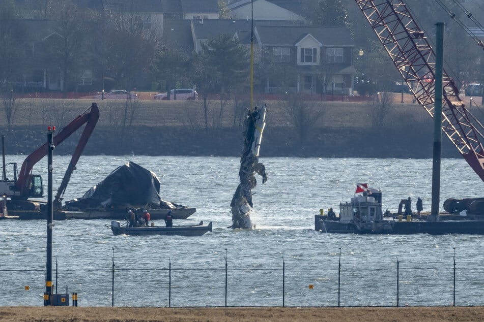 Ein Wrackteil wird aus dem Wasser auf ein Bergungsschiff in gehoben, wo ein American Airlines-Jet und ein Black Hawk-Hubschrauber in der Luft zusammengestoßen sind.