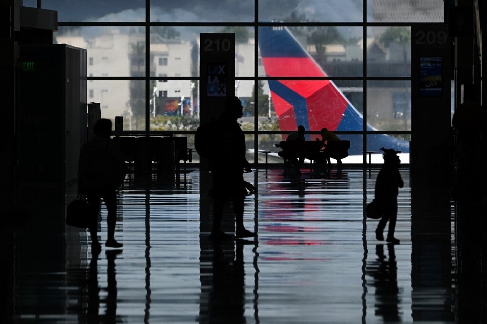 Passengers carry baggage as they walk to flights at Los Angeles International Airport (LAX).