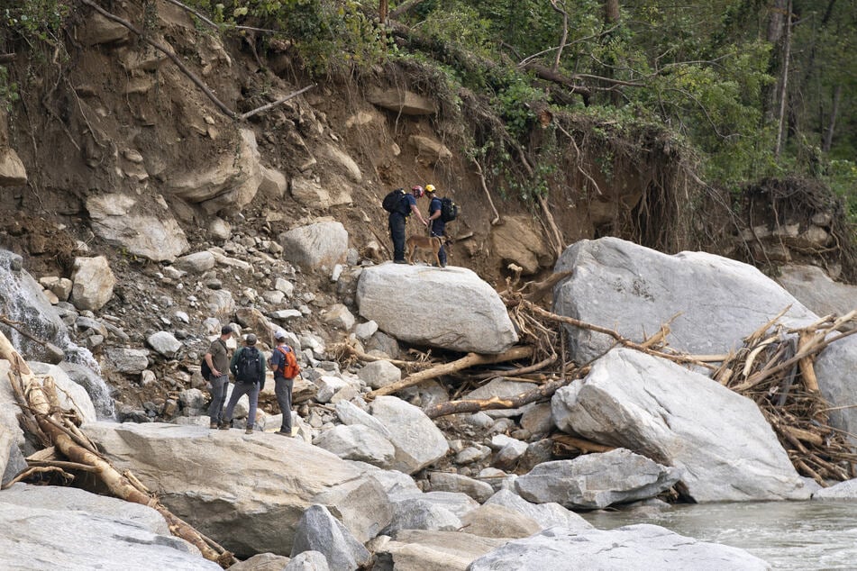 Search and rescue teams hike along the Broad River where North Carolina Route 9 used to be, in the aftermath of Hurricane Helene on Wednesday near Chimney Rock, North Carolina.