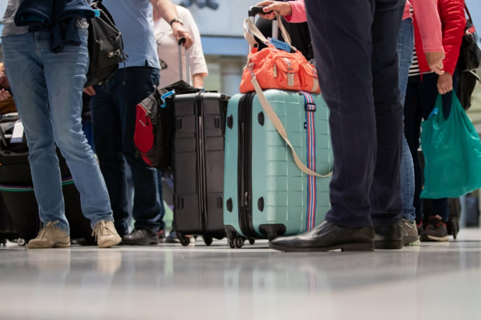 Passagiere eines Rückholfluges aus Ägypten stehen mit ihrem Gepäck im Flughafen.