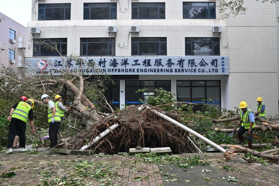 Workers cut and remove a fallen tree following the passage of Super Typhoon Ragasa in Yangjiang, in southern China’s Guangdong province, on September 25, 2025.
