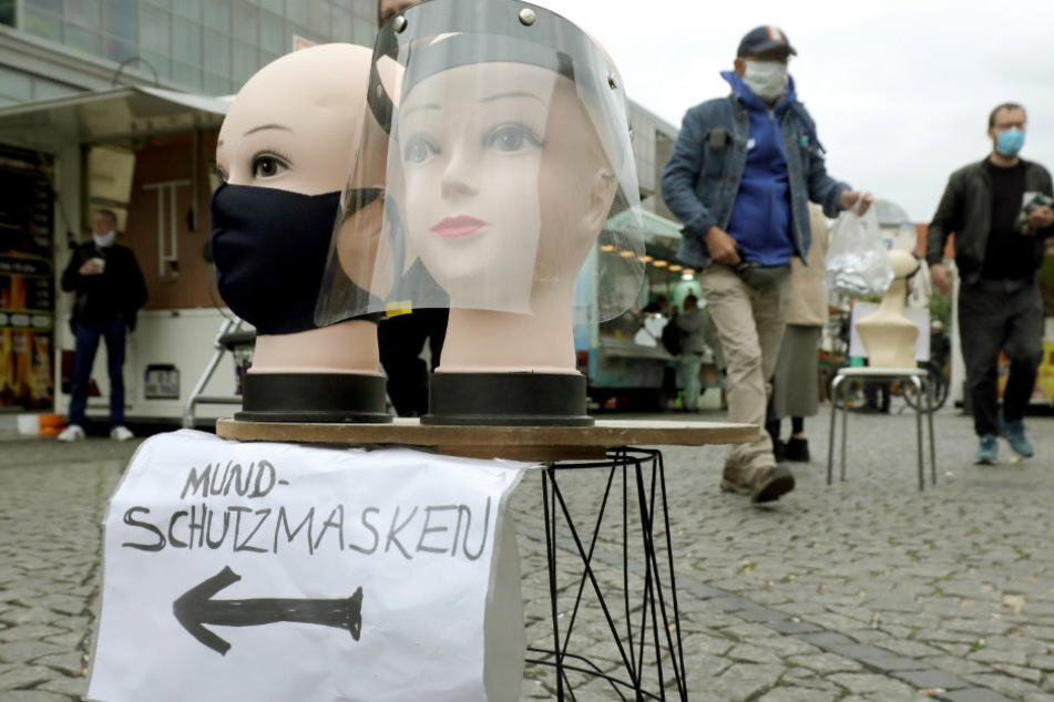 Menschen gehen über einen Wochenmarkt auf dem Hermannplatz im Bezirk Neukölln, auf dem Mund- und Schutzmasken zum Kauf angeboten werden.