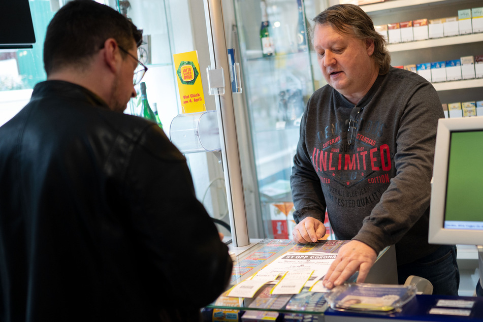 Kioskbetreiber Michael Fellendorf nimmt in seinem Geschäft einen Lottoschein an. Nicht jeder kann in Zeiten von Corona von zuhause aus sein Geld verdienen.
