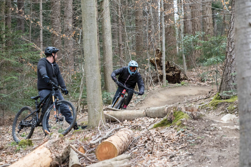 Ein Mountainbiker fährt mit seinem Fahrrad den Trail "Borderline" in Freiburg herunter, während ein anderer Mountainbiker zusieht. Der anhaltende Lockdown zieht nach Schätzungen von Experten mehr Menschen als üblich in die Wälder.
