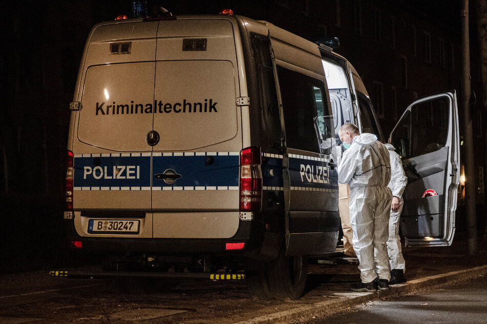Kriminaltechniker der Polizei stehen am frühen Morgen an ihrem Einsatzfahrzeug an einem Wohnhaus im Berliner Bezirk Reinickendorf.