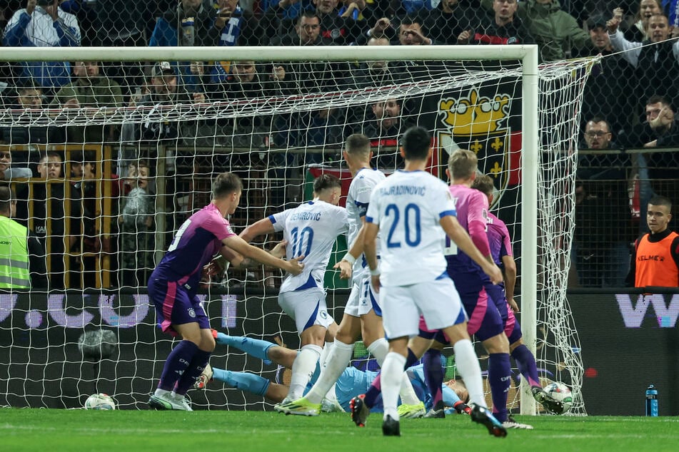 Edin Dzeko (M.) schaut den Ball beim Einschlag zum 1:2-Anschluss für Bosnien zu.