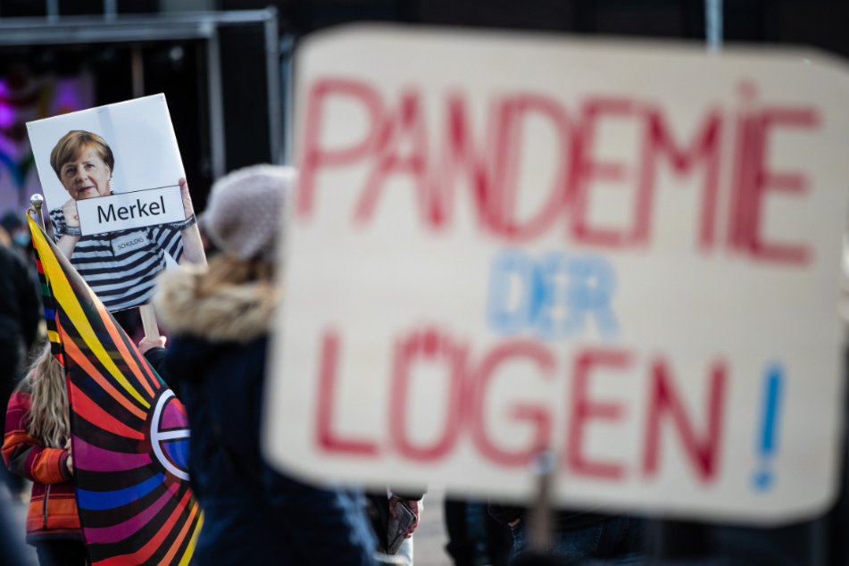 Göppingen: "Pandemie der Lügen!" steht auf dem Schild eines Teilnehmers geschrieben, der an einer Demonstration gegen die Corona-Politik der Bundesregierung teilnimmt. Im Hintergrund ist ein Schild zu sehen, auf dem Bundeskanzlerin Merkel in "Sträflingskleidung" abgebildet ist.