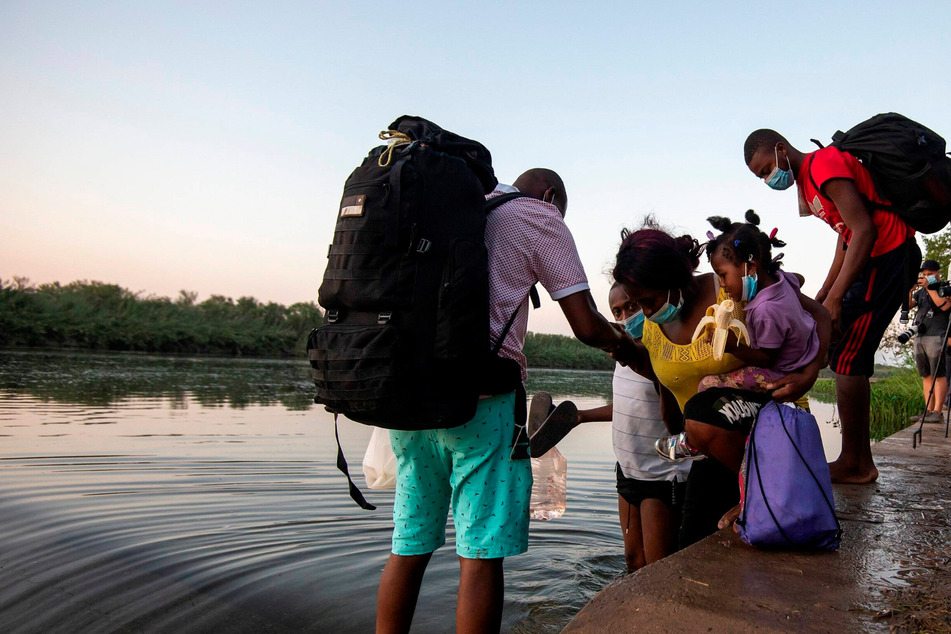 A group of Haitian migrants begins to cross the Rio Grande from Mexico into Texas.