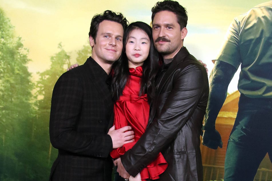 Jonathan Groff (r), Kristen Cui (c), and Ben Aldridge star as an unassuming family whose vacation turns bloody in the horror flick, Knock at the Cabin.