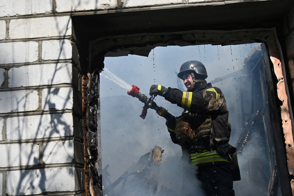 Ein Feuerwehrmann bei Löscharbeiten in einem zerbombten Haus in Charkiw.
