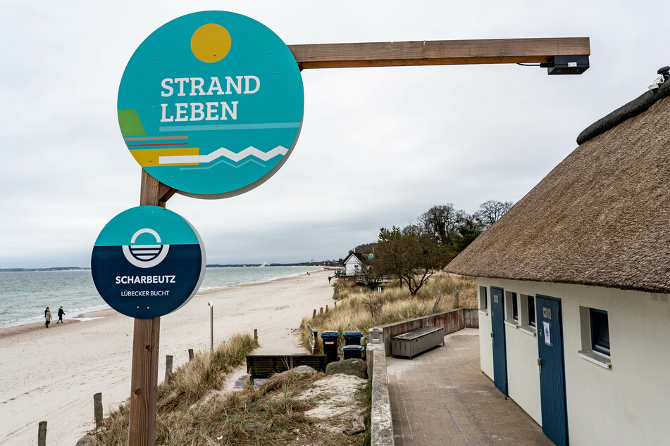 Eine Strandampel, ein elektronisches Zählsystem, welches an einem Lattenkreuz (rechts oben) befestigt ist und gemeinsam mit einer App die Belegung des Strandes errechnet steht am Zugang zum Strand von Scharbeutz.