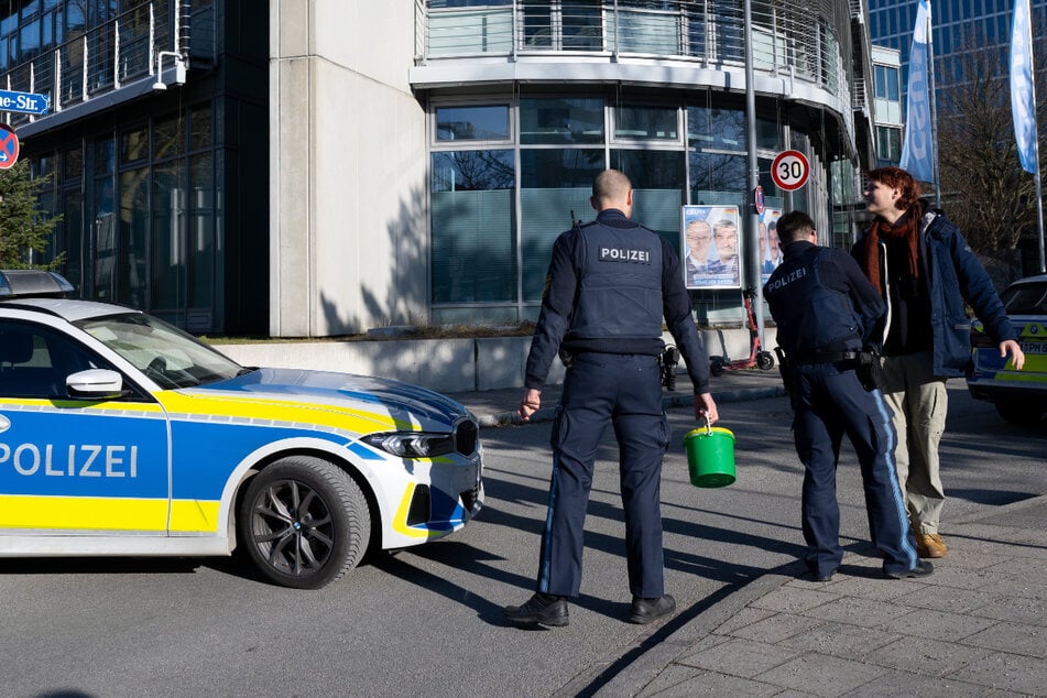 Polizisten durchsuchen die Taschen von einem Aktivisten vor der CSU-Zentrale.