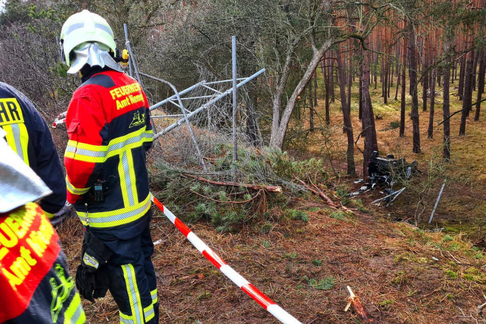 Ein Feuerwehrmann blickt die Böschung hinunter, wo der völlig zerstörte Ford auf dem Dach liegt.