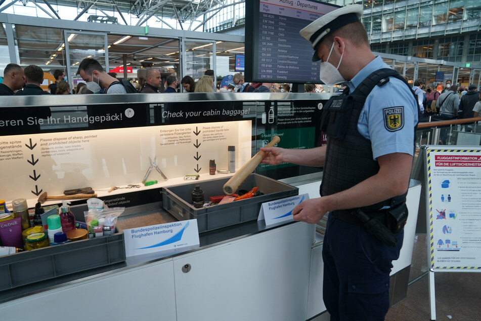 Ein Bundepolizei zeigt die konfiszierten Gegenstände am Flughafen Hamburg, darunter eine Pfeffermühle in Form eines Baseballschlägers.
