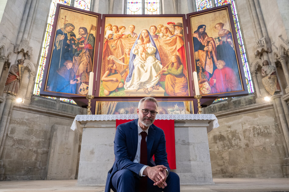 Der Leipziger Künstler Michael Triegel (53) sitzt im Dom zu Naumburg vor einem dreiflügeligen Altaraufsatz, für den er den Mittelteil geschaffen hat.