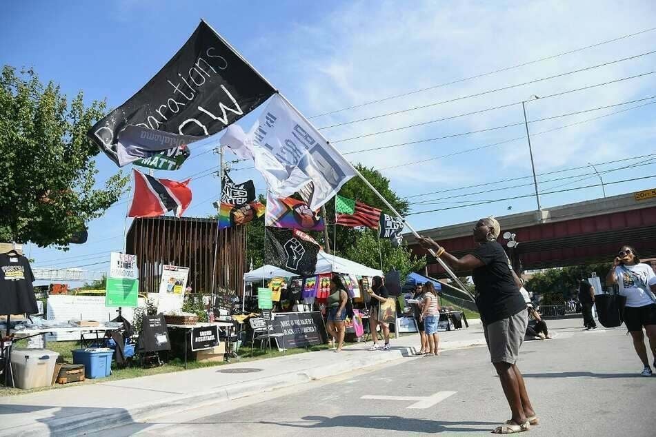 A woman in Tulsa, Oklahoma, waves a "Reparations Now" flag during Juneteenth celebrations.