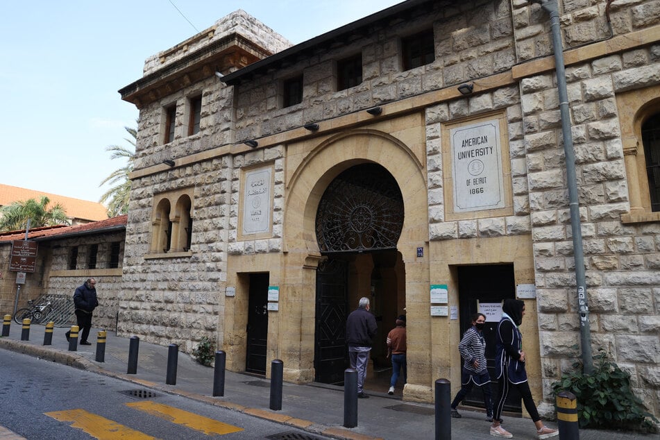 People walk past the main gate to the campus of the American University of Beirut in the center of the Lebanese capital.