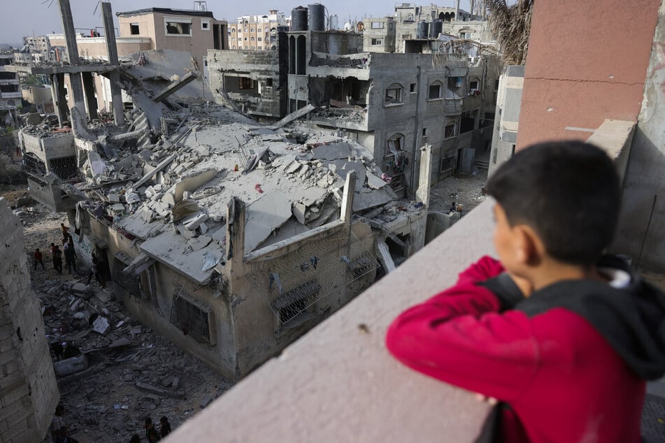 A Palestinian child looks out at a house destroyed in Israeli strikes in the al-Saftawi area west of Jabalia in the northern Gaza Strip on May 18, 2025.