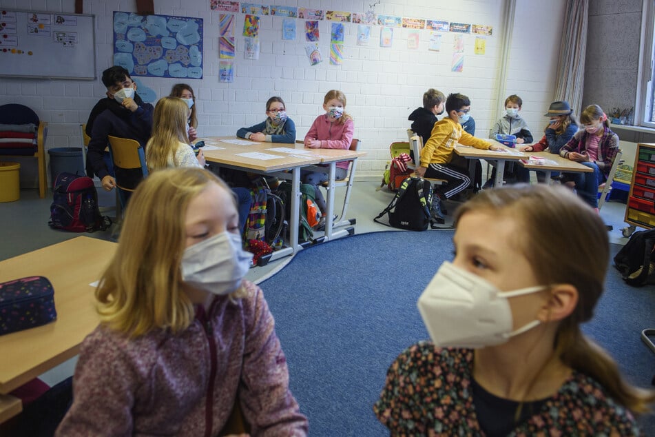 Schüler und Schülerinnen einer 4. Klasse sitzen im Unterricht an einer Grundschule zusammen an einem Tisch und tragen dabei einen Mund-Nasen-Schutz. In Thüringen wird die Maskenpflicht ab kommenden Montag für alle Klassenstufen gelten.
