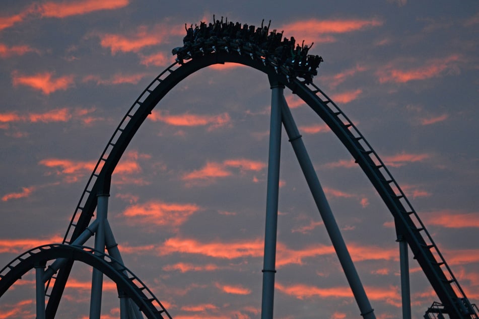 Besucher des Europa-Parks in Rust fahren in der Sonnenuntergangsstimmung mit der Achterbahn "Silverstar".