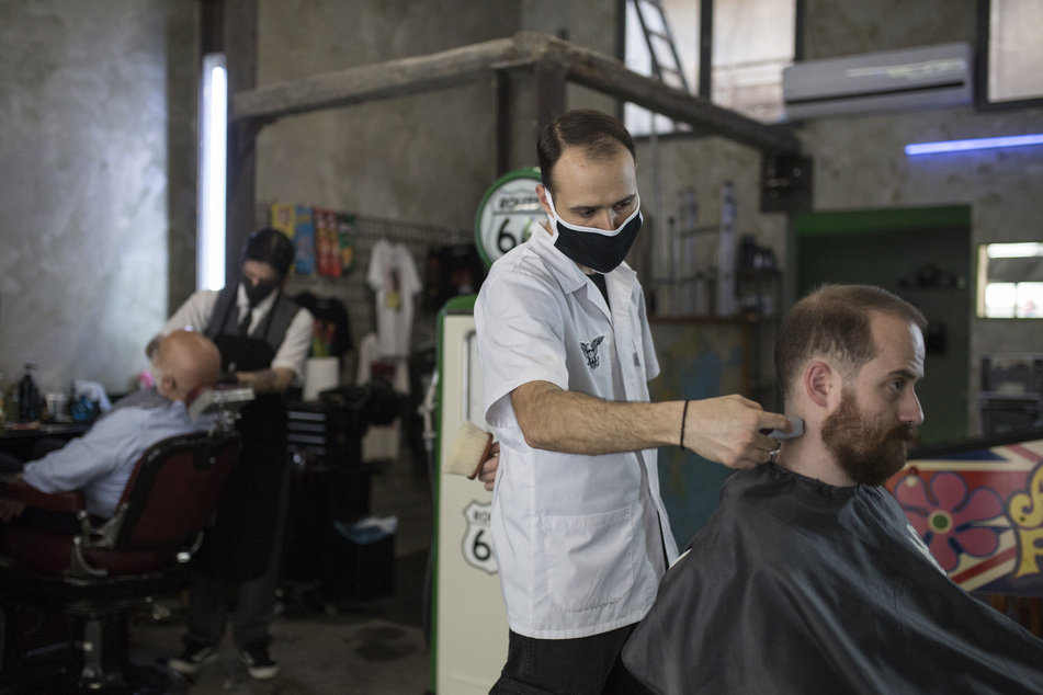 Ein Barbier rasiert einen Mann in einem Friseurladen.
