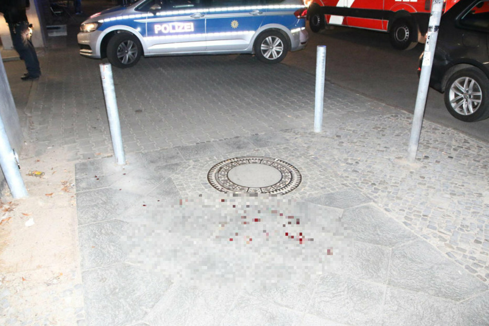 Blut ist neben einem Gullydeckel auf dem Bürgersteig zu sehen.