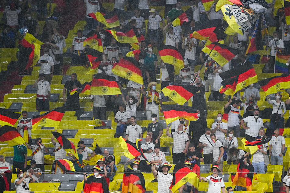 Deutsche Fans feuern unter starkem Regen ihre Mannschaft in München an.