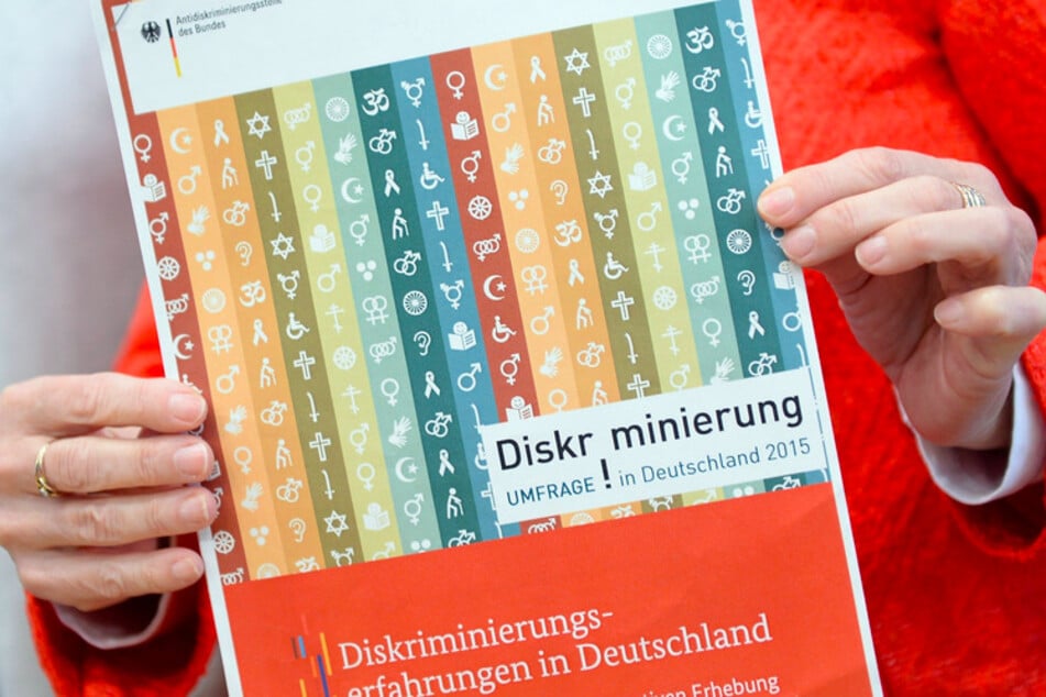 Die Leiterin der Antidiskriminierungsstelle des Bundes zeigt in Berlin während der Pressekonferenz zu der Umfrage "Diskriminierung in Deutschland" den Bericht.