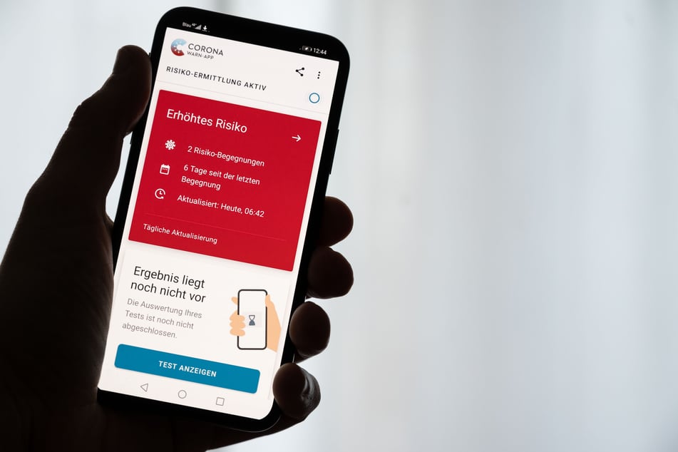 Ein Mann hält ein Smartphone in der Hand, auf dem die Corona-Warn-App der Bundesregierung ein erhöhtes Risiko anzeigt (gestellte Szene).