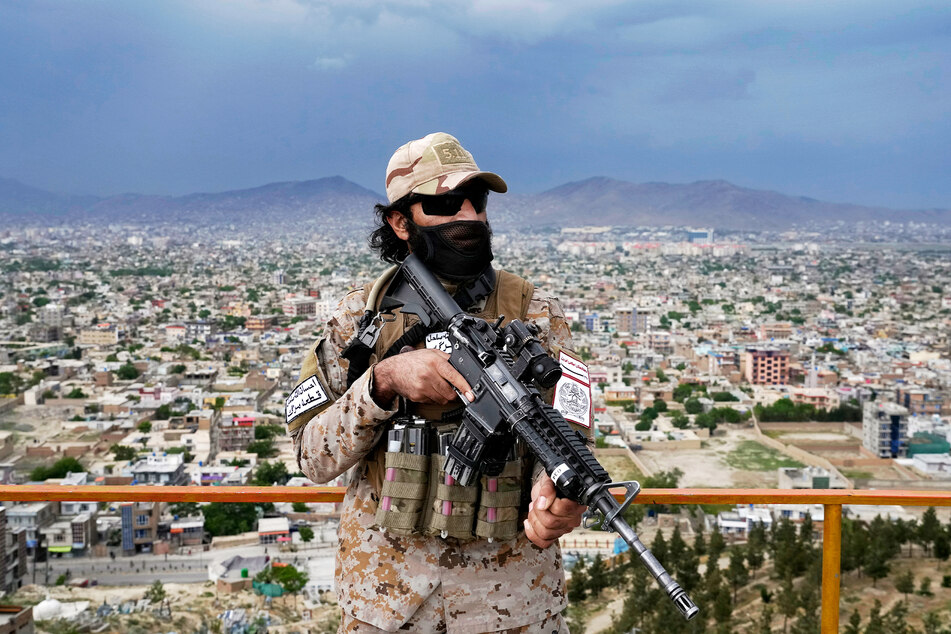 Ein Mitglied einer Taliban-Spezialeinheit steht mit einem Gewehr in einem Park.