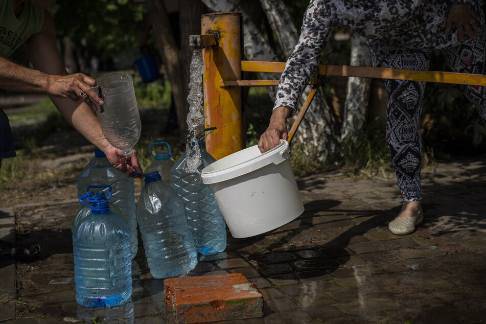 Anwohner in Slowjansk holen frisches Wasser mit einer Pumpe aus einem Brunnen. Trinkwasser ist in der Ukraine wegen des russischen Angriffskrieges ein rares Gut geworden - wie etwa Strom und Gas auch.