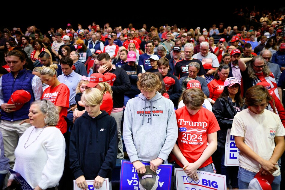 Supporters of presidential candidate Donald Trump bowing their heads in prayer during a rally in Rome, Georgia, on March 9, 2024.
