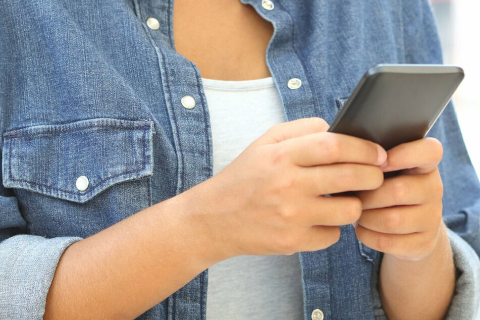 Eine Frau hält ein Smartphone in ihren Händen (Symbolbild).
