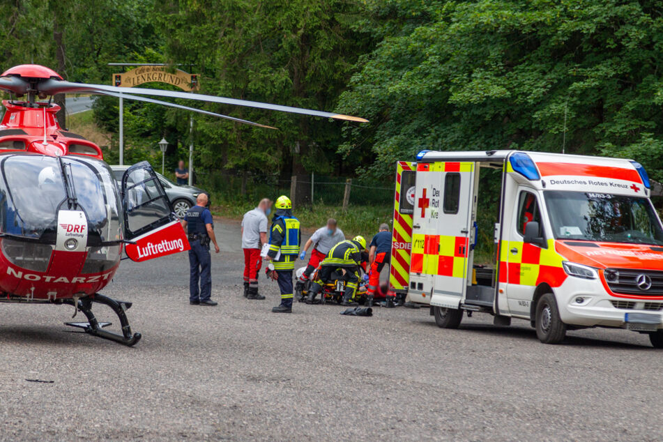 Ein Hubschrauber samt Krankenwagen steht am Unfallort. Dahinter kümmern sich die Einsatzkräfte um den Verletzten.