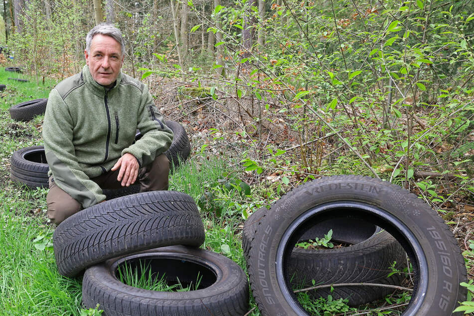 Revierförster Frank Günther (57) kniet neben den im Wald entsorgten Reifen.