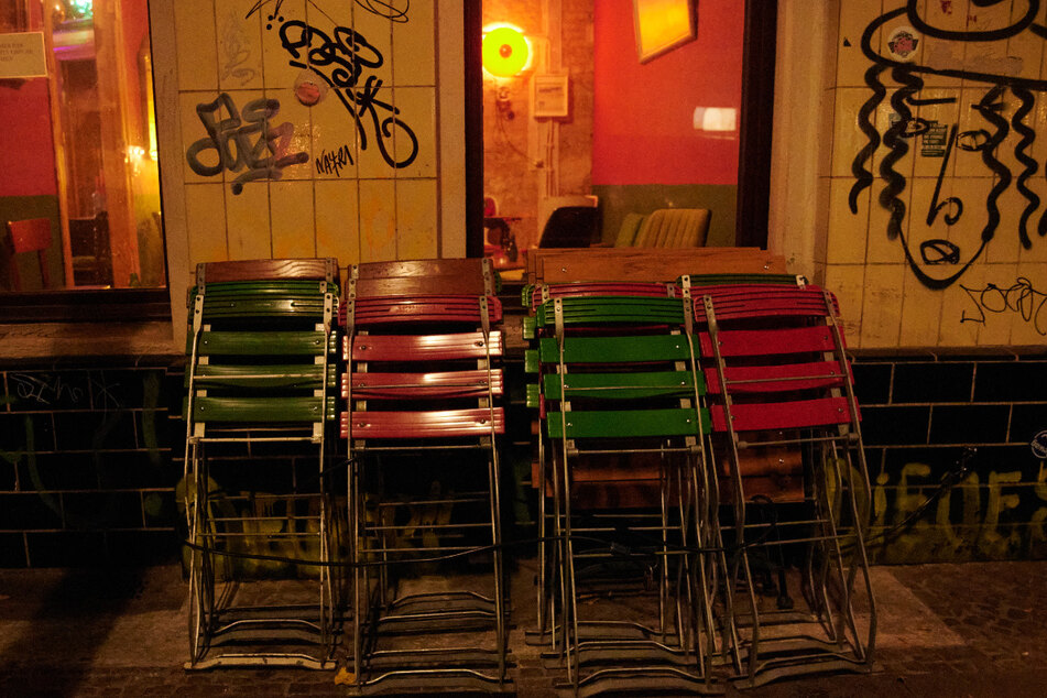 Kurz nach der Sperrstunde stehen zusammengeklappte Stühle vor einer Bar in Berlin-Neukölln. Wegen der Corona-Pandemie gelten eine nächtliche Sperrstunde und strengere Kontaktverbote für drinnen und draußen.