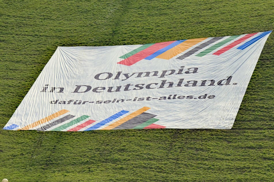Ein Banner mit der Aufschrift "Olympia in Deutschland. dafür-sein-ist-alles.de" liegt auf dem Olympiaberg in München.