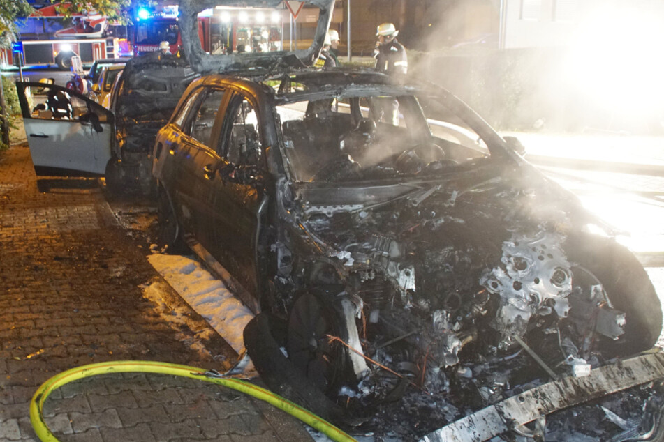 Die Feuerwehr löscht die ausgebrannten Autos.