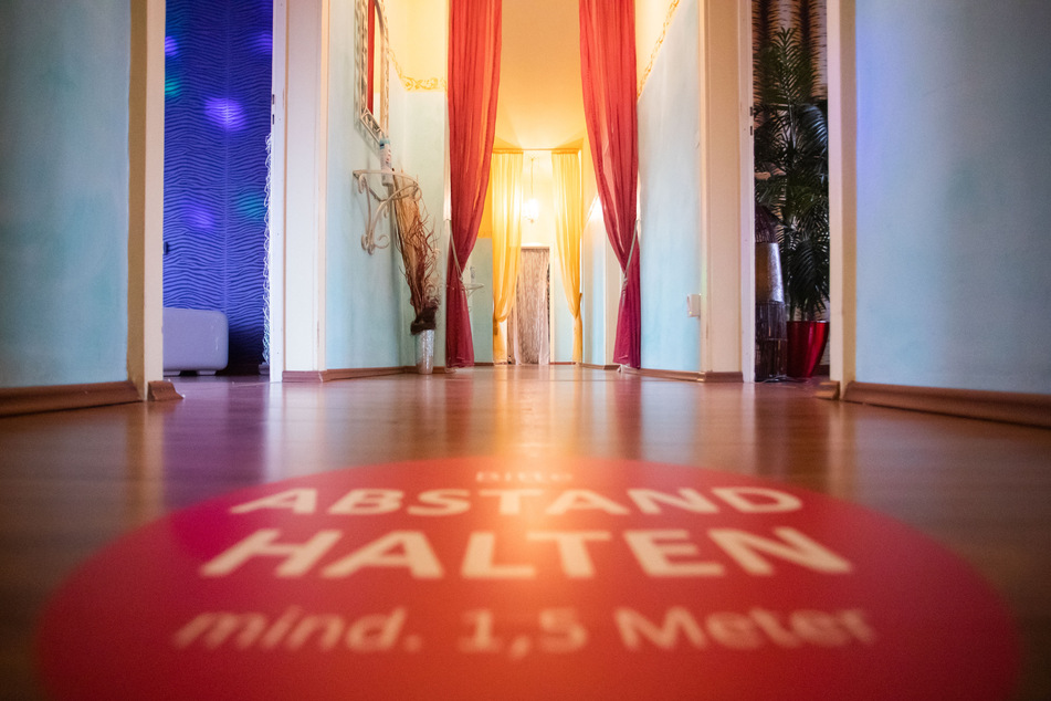 Auf einem Gang ist ein Aufkleber mit der Aufschrift "Bitte Abstand halten, mind. 1,5 Meter" angebracht.