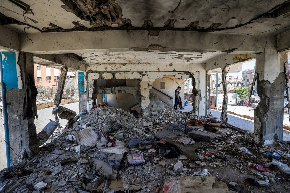 Boys walk past a destroyed classroom where people were sheltering at a school run by UNRWA that was previously hit by Israeli bombardment, in the Nuseirat camp in the central Gaza Strip.