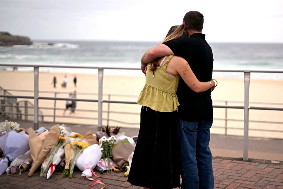 Mourners embrace near tributes piled together in memory of the victims of a shooting at Bondi Beach, in Sydney on Tuesday.