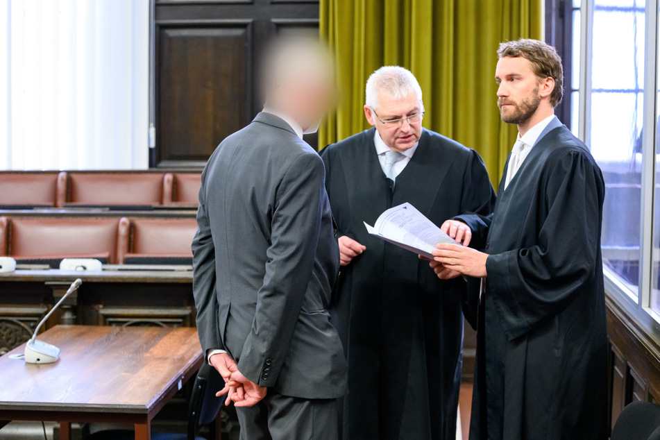Ein angeklagter Arzt (l.) steht neben Rechtsanwälten Leon Kruse (r.), Ulrich Steffen (2.v.r.) im Sitzungssal. Die Verteidiger forderten am Donnerstag Freispruch. Ursprünglich hatte das Gericht anschließend sein Urteil verkünden wollen.