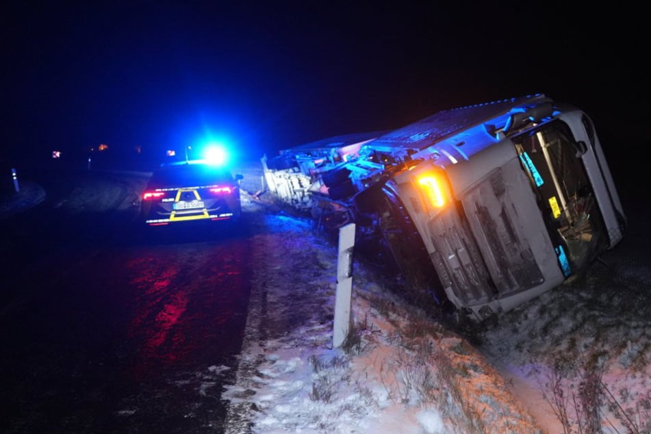 Laster rutscht auf schneeglatter Fahrbahn in Straßengraben und kippt um