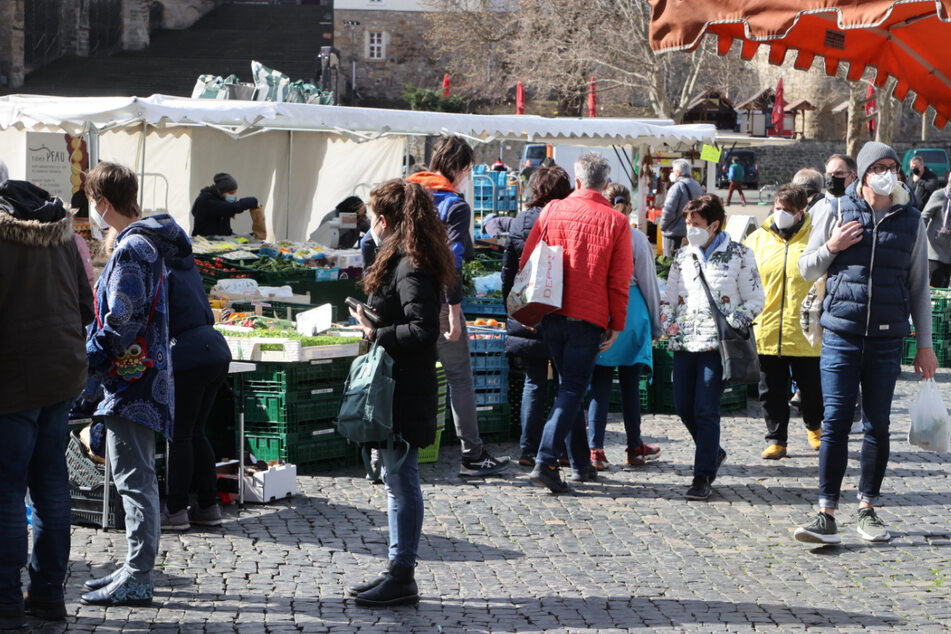 Menschen warten mit Abstand an einem Gemüsestand auf dem Erfurter Domplatz, wo der wöchentliche Markt stattfindet. In Thüringen ist die Inzidenz gesunken. Drei Städte haben inzwischen einen Wert von unter 100.